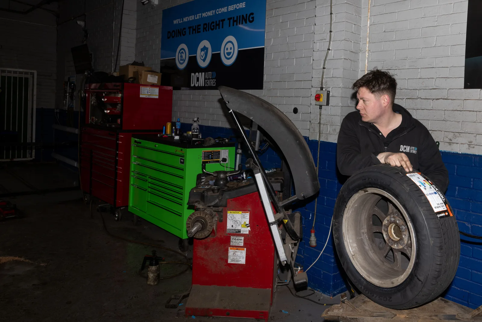 DCM technician with a new tyre at the wheel balancing machine