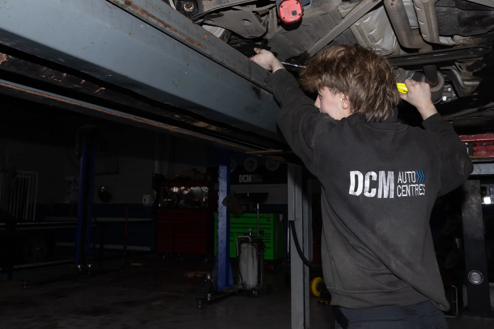 Technician inspecting the underside of a car on the lift