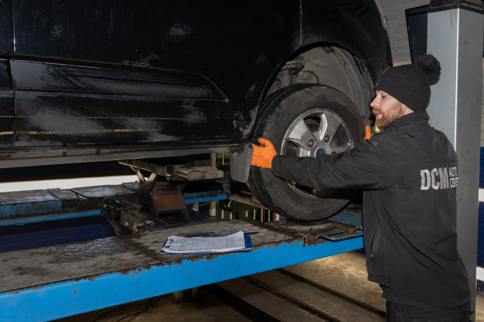 Technician inspecting a wheel and suspension on the workshop lift